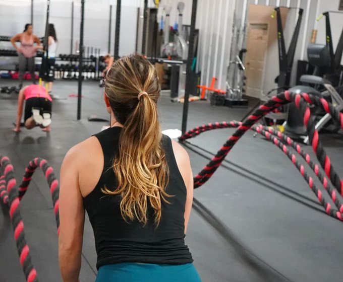 Women training with battle ropes in a bright fitness studio